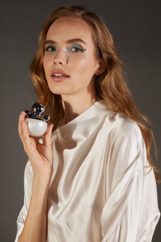 A model in white with a white vanilla perfume bottle