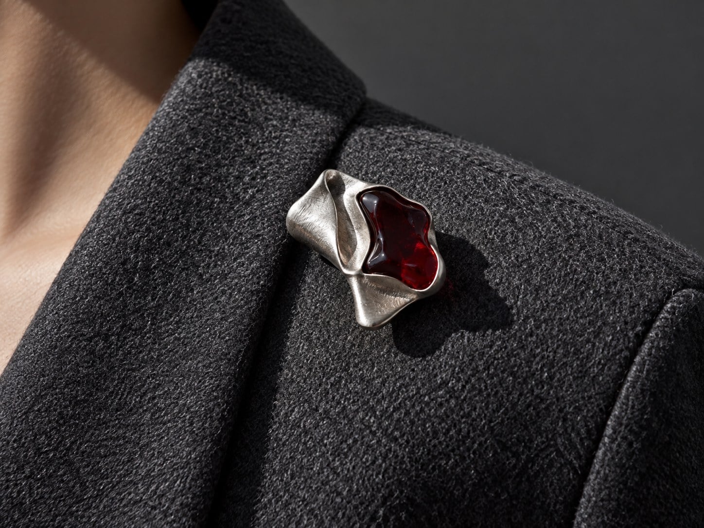 A small sculptural silver brooch with a dark red