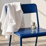 A white cotton shirt rests on a blue metal chair