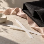 Two perfume blotters beside blush silk and dark