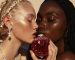Close up of two models holding and kissing a luxurious crystal and red round perfume bottle